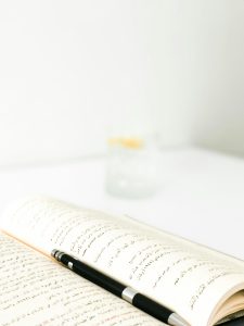 Open book with Arabic script and pen on a white table. Minimalist style.